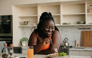 Woman smiling while eating lunch in kitchen