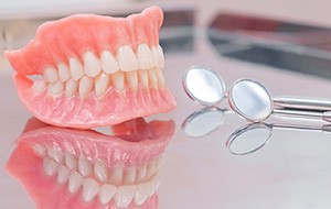 Two dentures laying on a glass countertop