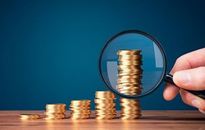 A magnifying glass inspecting a stack of coins