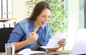 Woman celebrating the low cost of her dentures