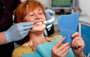 Woman smiling while looking in dental mirror