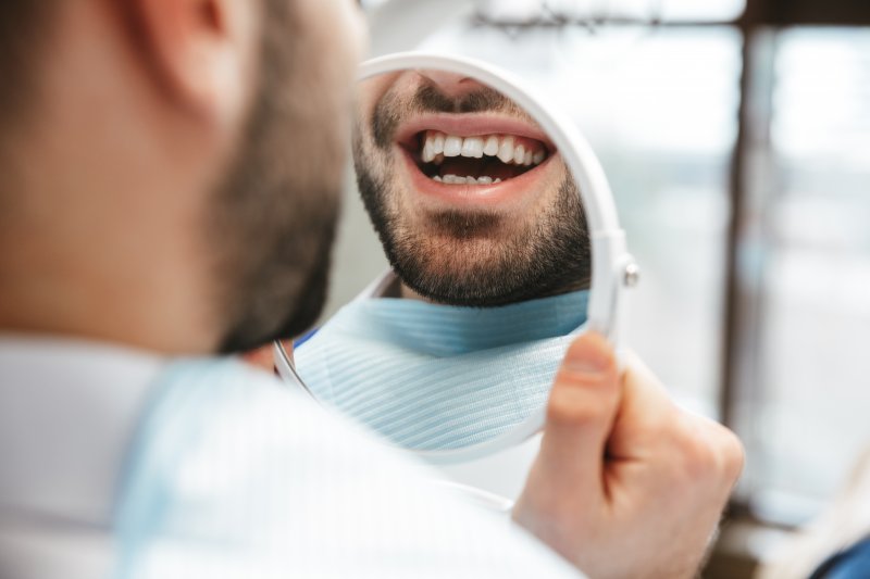 Patient smiling in the mirror at their veneers