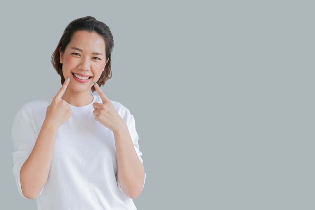 Woman smiling while pointing to clear aligners