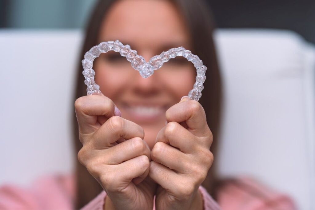 A woman holding Invisalign aligners